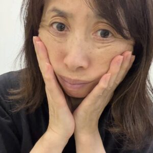50代_顔のたるみを触る女性