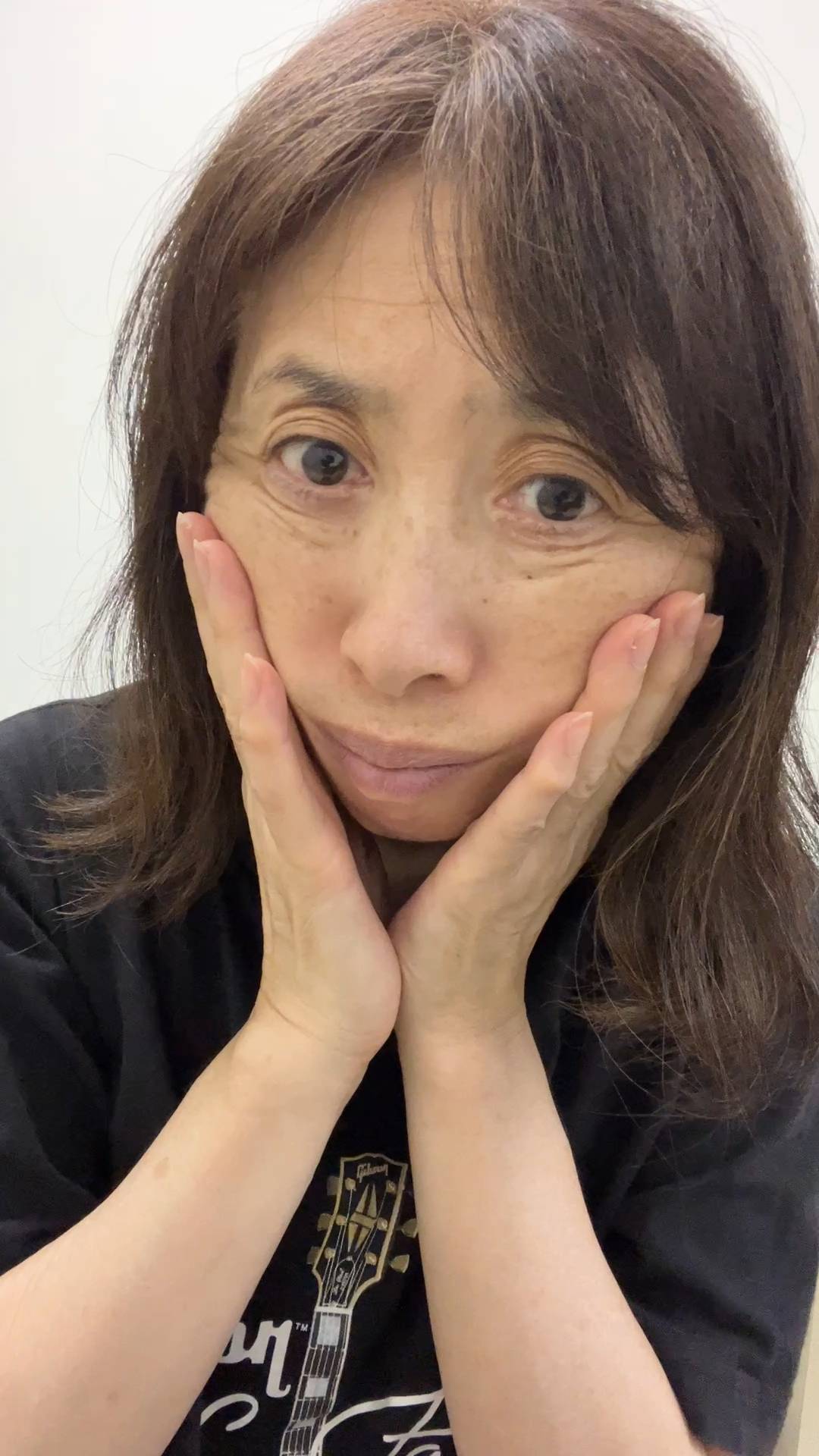 50代_顔のたるみを触る女性