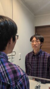 鏡を見てにっこり笑う男性