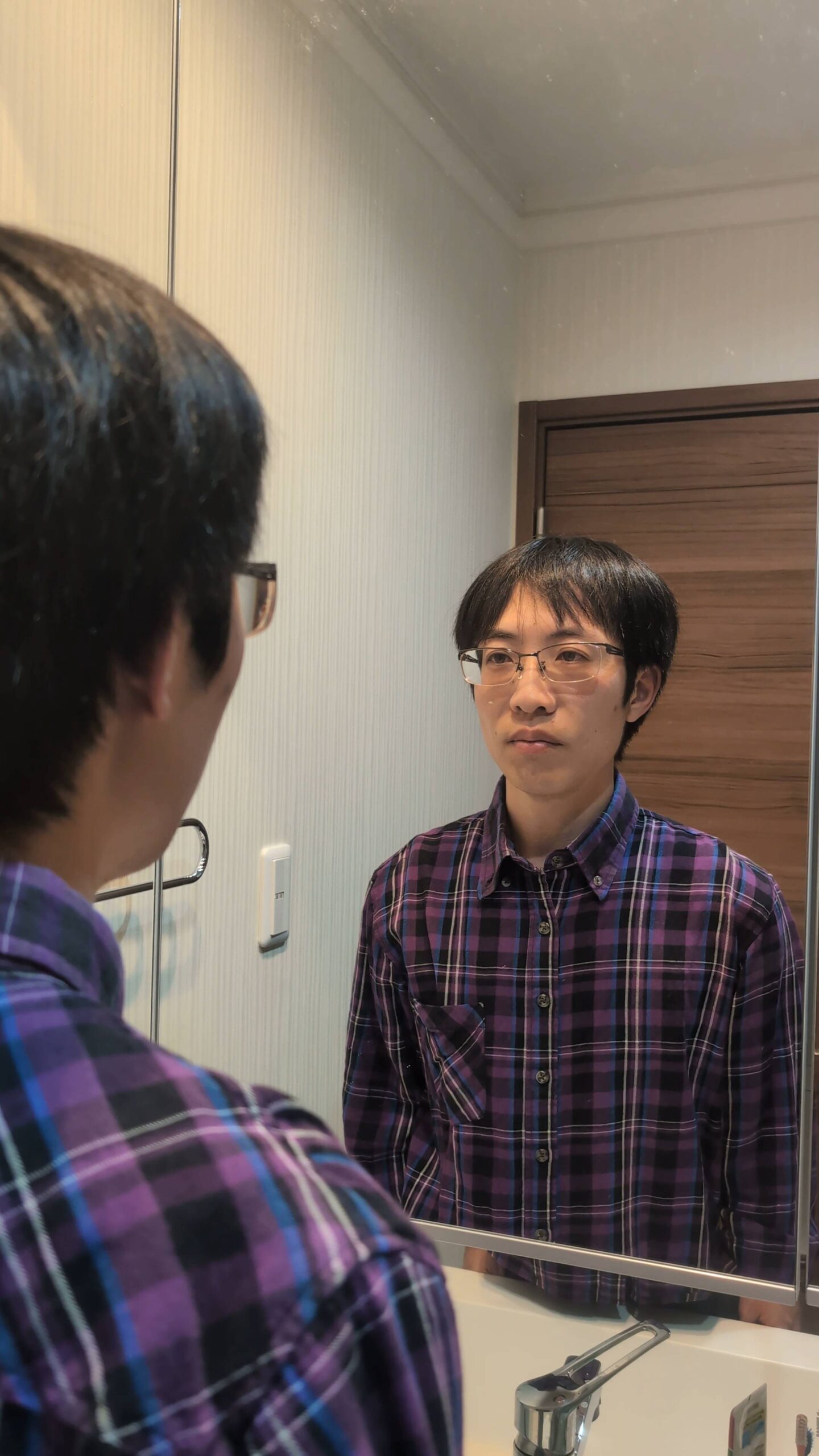 鏡に向かって笑顔練習する男性