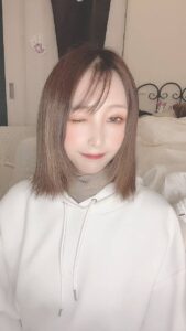 カメラを見てウインクする女性｜笑顔