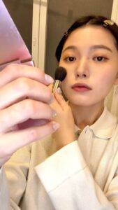 チークをブラシでのせて笑う女性｜ヘルスケア｜メイク