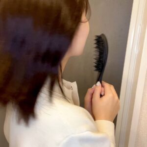 ヘアブラシを持って振り向き笑顔の女性｜笑顔｜ヘアブラシ｜準備｜ヘアケア