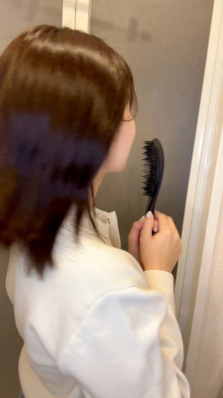ヘアブラシを持って振り向き笑顔の女性｜笑顔｜ヘアブラシ｜準備｜ヘアケア
