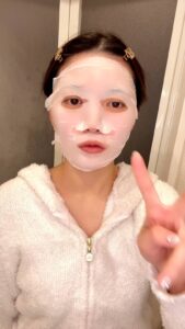 パック中に笑ってピースする女性｜スキンケア｜パック｜日常｜パジャマ