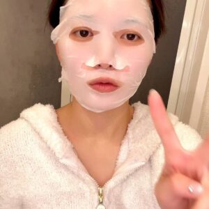 パック中に笑ってピースする女性｜スキンケア｜パック｜日常｜パジャマ