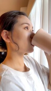 コーヒーを飲みながら目を閉じて満足顔な女性｜笑顔｜コーヒー｜朝日