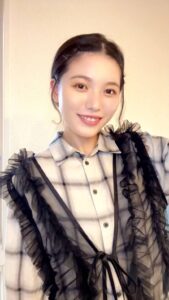 カメラに向かって笑顔でピースサインをする女性