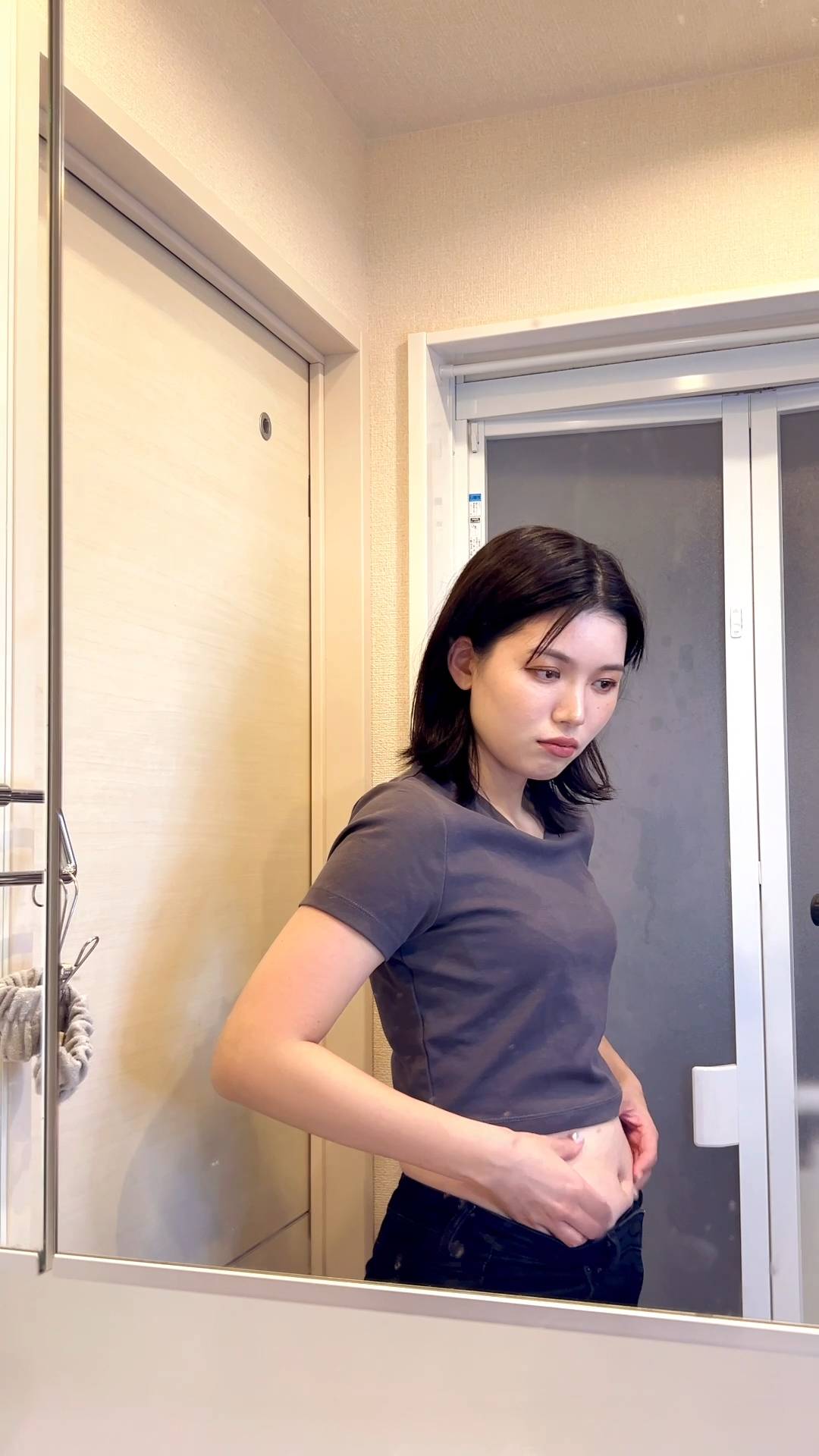 ちょっと不満げにスタイルチェックをする女性｜鏡越し｜悩み｜お腹