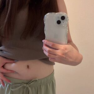 鏡越しにお腹つまむ女性｜ダイエット｜痩身｜肥満
