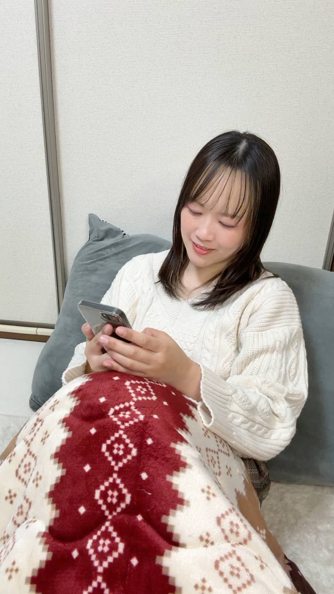 自宅でくつろいでスマホを操作する女性｜日常